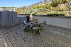 Patio with table, chairs, surfboards, wetsuits and beer