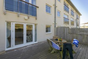 Patio with table, chairs, beer, surfboards and wetsuits