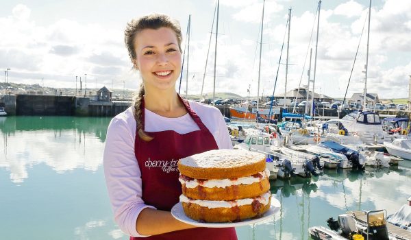 Woman holding 3 tier cake with harbour in the background