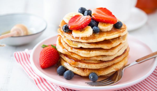 American-style pancakes with strawberries, banana, blueberries and maple syrup