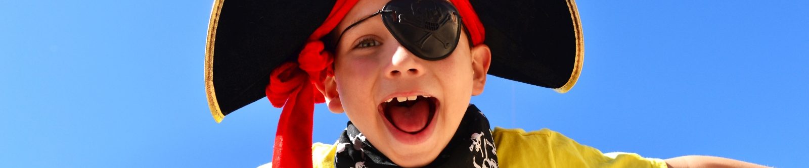 Child dressed as a pirate against a blue sky background