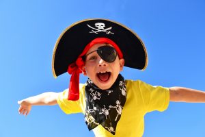 Child dressed as a pirate against a blue sky background