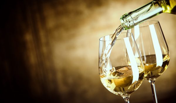 Pouring two glasses of white wine from a bottle
