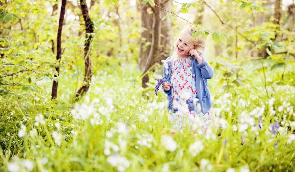little girl holding bluebells in the woods